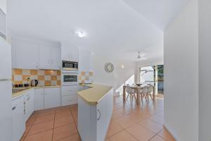 a kitchen with white cabinets and a table with chairs at Beach Court - Airlie Beach in Airlie Beach