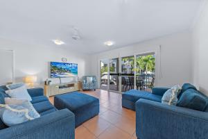 a living room with two blue couches and a tv at Beach Court - Airlie Beach in Airlie Beach