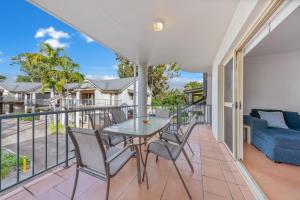 a balcony with a table and chairs and a couch at Beach Court - Airlie Beach in Airlie Beach
