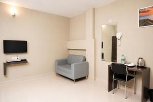 a room with a chair and a desk and a television at Vilasa Prime Hotel in Guwahati
