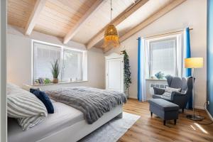 a bedroom with a bed and a chair and windows at Blaues Haus in Buchloe