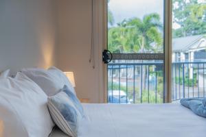 a bedroom with a bed with pillows and a window at Beach Court - Airlie Beach in Airlie Beach +23 photos