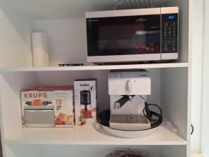 a kitchen shelf with a coffee maker and a microwave at Fiore apartment & room in Krk