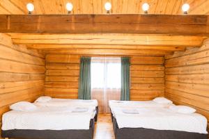 two beds in a room with wooden walls and a window at Privaatne maja metsas, kraanist voolab allikavesi in Plaani