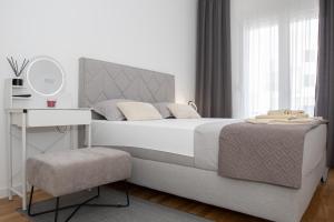 a white bedroom with a bed and a table and a mirror at Apartman Solis in Trebinje