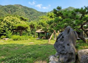 a statue in a field with a mountain in the background at Gapyeong Yunseul Pension in Chuktul-li +5 photos