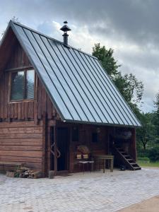 a log cabin with a metal roof and a table at Privaatne maja metsas, kraanist voolab allikavesi in Plaani