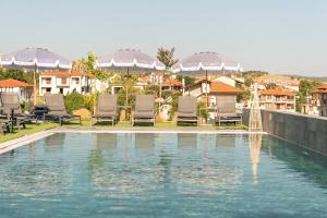 a swimming pool with chairs and umbrellas in a city at Pnoe Boutique suites in Nikiti