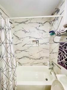 a bathroom with a white tub and a marble wall at Hopes Cozy Condo in Phoenix