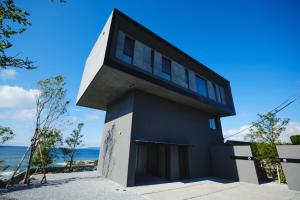 a black and white house with the ocean in the background at THE THIRD PLACE tatéyama 楼 in Tateyama