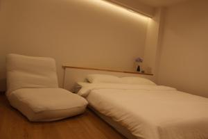 two beds with white sheets and a chair in a room at Leisure Hotel II 東中野 in Tokyo