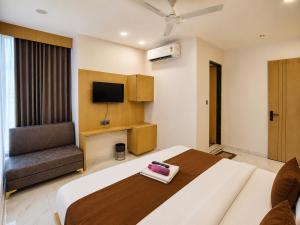 a bedroom with a bed and a chair and a television at Hotel Elite in Ahmedabad