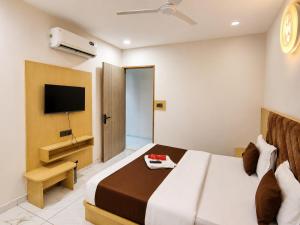 a hotel room with a bed and a flat screen tv at Hotel Elite in Ahmedabad
