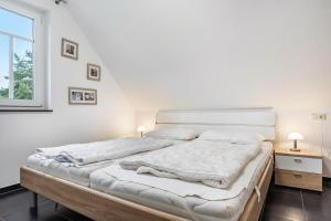 a white bedroom with a large bed and a window at Haus 50 in Röbel