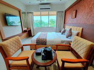 a hotel room with a bed and a table and chairs at Hotel Sai Residency in Karjat