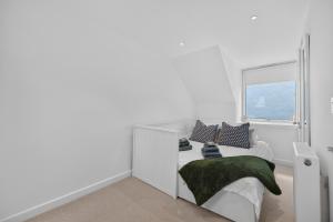 a white bedroom with a bed with a window at Conners in Gardenstown