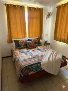 a bedroom with a bed with colorful blankets and pillows at Tevaatua house in Papara