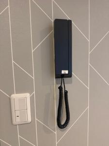 a phone hanging on a wall with a cord at Guest house雅 in Matsudo
