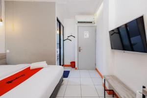 a bedroom with a bed and a flat screen tv at RedDoorz near Mangga Dua Mall in Jakarta +18 photos