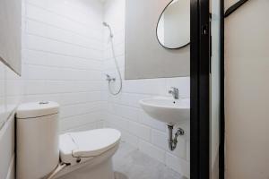 a white bathroom with a toilet and a sink at RedDoorz near Mangga Dua Mall in Jakarta