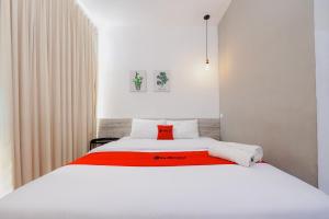 a bedroom with a white bed with a red blanket at RedDoorz near Mangga Dua Mall in Jakarta