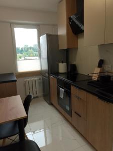 a kitchen with a refrigerator and a table and a window at Apartament Kaszmirowy in Gorlice