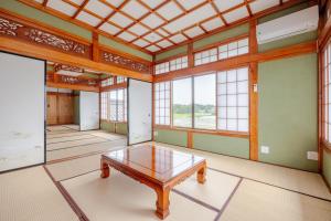 an empty room with a table in a room with windows at ジャポニークハウス in Sanmu