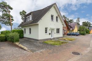 a white house with a black roof on a street at Haus 7 in Röbel