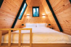 a bed in a wooden cabin with two windows at YEYU Hotel in Dujiangyan