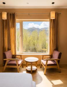 a room with two chairs and a table and a window at Hotel Dekiling by Eastlynn Collections in Leh