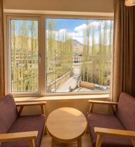 a room with two chairs and a large window at Hotel Dekiling by Eastlynn Collections in Leh