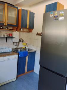 a kitchen with a stainless steel refrigerator and blue cabinets at Apartmani Dević Šušanj in Bar