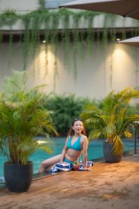 a woman in a bikini sitting next to a pool at Aurum by R J Resorts in Siliguri