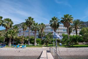 a large building with palm trees and chairs on a beach at HOTEL SISSY in Kamena Vourla