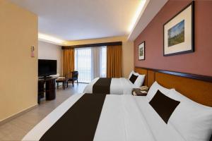 a hotel room with a large bed and a television at Sunday Residence Inn Cherating in Cherating