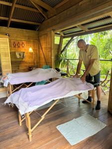 a man making two beds in a room at Bambou cabane intimiste in Saint-Louis