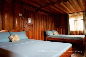 two beds in a room with wooden walls at Baey Bōgan Homestay in Sagada +33 photos