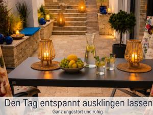 a table with two candles and a bowl of fruit at Die Perle am Teich ist Ihre exklusive Ferienwohnung mit Klimaanlage und großer Terrasse im Harz in Ballenstedt