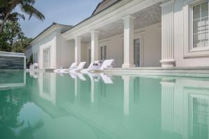a house with a swimming pool with white chairs at MansionHaus in Anjuna