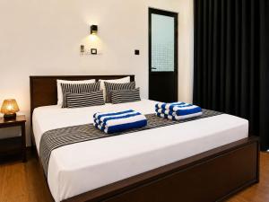 a bedroom with a large bed with blue and white pillows at Coco Palm Villa and Cabanas in Tangalle