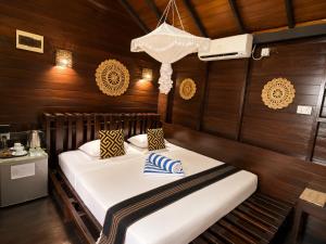 a bed in a room with wooden walls at Coco Palm Villa and Cabanas in Tangalle