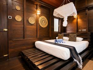 a bedroom with two beds and a wooden wall at Coco Palm Villa and Cabanas in Tangalle