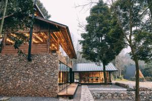 a house with a stone wall and a tree at YEYU Hotel in Dujiangyan +17 photos