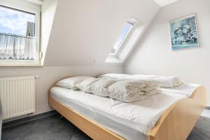 a bed with white sheets in a room with two windows at Haus S 42 in Röbel
