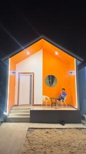 a man sitting on a chair in front of a house at ปลายเขื่อนแคมปิ้ง บ้านวิวเขื่อน in Sirindhorn