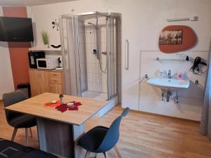 a bathroom with a shower and a table and a sink at Pension am Kirchberg - Zimmer 1 in Daun