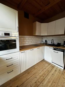 a kitchen with white cabinets and a wooden floor at J&K Apartments in Brocēni