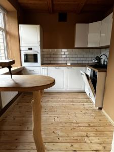 a kitchen with white cabinets and a wooden table at J&K Apartments in Brocēni +7 photos