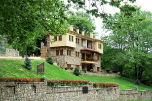 a large house on a hill behind a stone wall at Roes Suites in Kato Loutraki