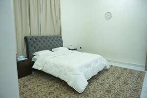 a bedroom with a white bed and a chair at Al Miqyal Resort - استراحة المقيال - الساد in Al Ain